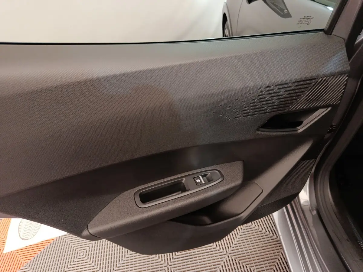 Vue rapprochée de la porte avant droite intérieure de la Renault Clio gris foncé, avec commandes de vitre électrique.