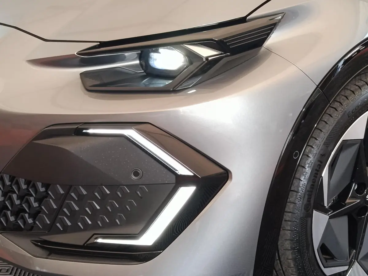 Gros plan sur l'avant droit de la Renault Clio Techno gris foncé, mettant en valeur le phare LED et la calandre géométrique.