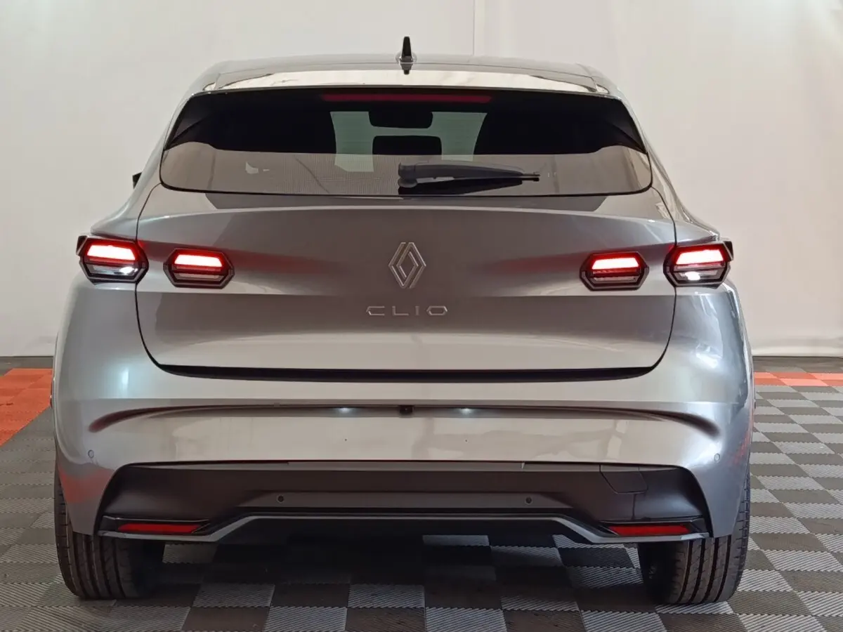 Vue arrière d’une Renault Clio gris foncé 2026 avec feux arrière LED allumés et lunette arrière teintée.