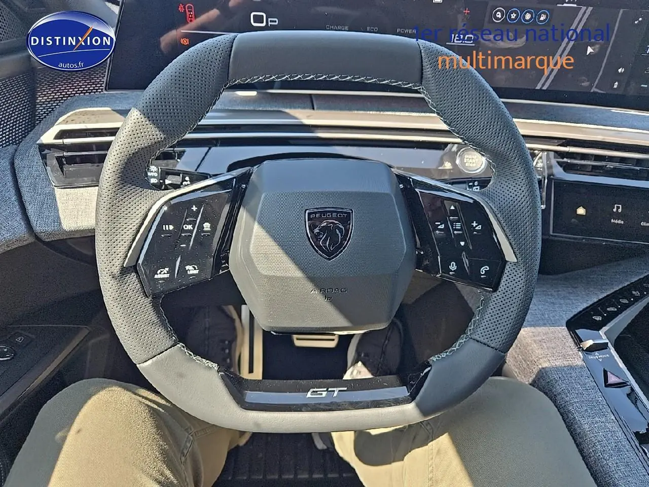 Vue rapprochée du volant cuir perforé gris titane du Peugeot 5008 Hybrid 145 GT avec commandes multifonctions intégrées.
