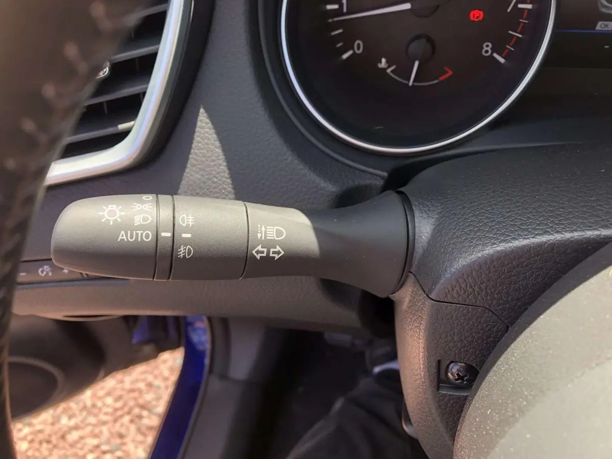 Gros plan sur la commande des feux et clignotants à gauche du volant du Nissan Qashqai bleu 2019.