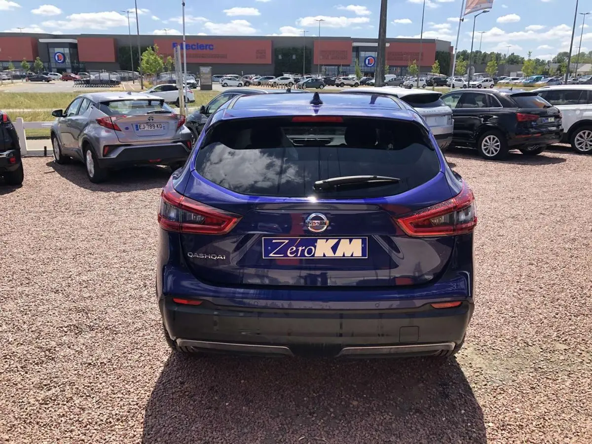 Vue arrière d'un Nissan Qashqai bleu métallisé, avec feux arrière allongés et plaque d'immatriculation "Zero KM" visible.