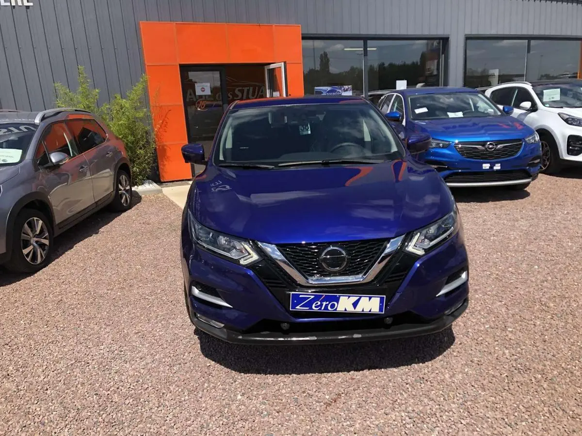 Vue de face d'un Nissan Qashqai bleu métallisé avec calandre chromée et plaque d'immatriculation Zero KM.