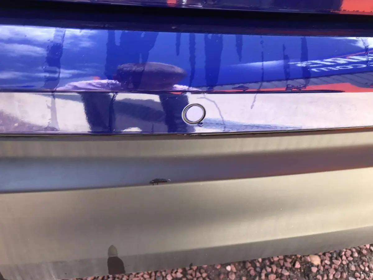 Gros plan sur le pare-chocs arrière bleu métallisé du Nissan Qashqai 2019 avec capteur de stationnement visible.