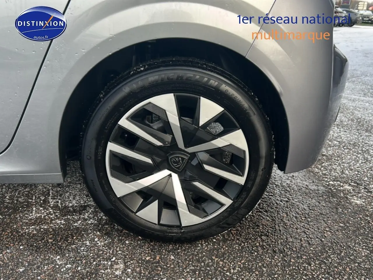 Gros plan sur la roue avant droite gris artense d'une Peugeot 208 1.2 100 style avec jante au design géométrique.