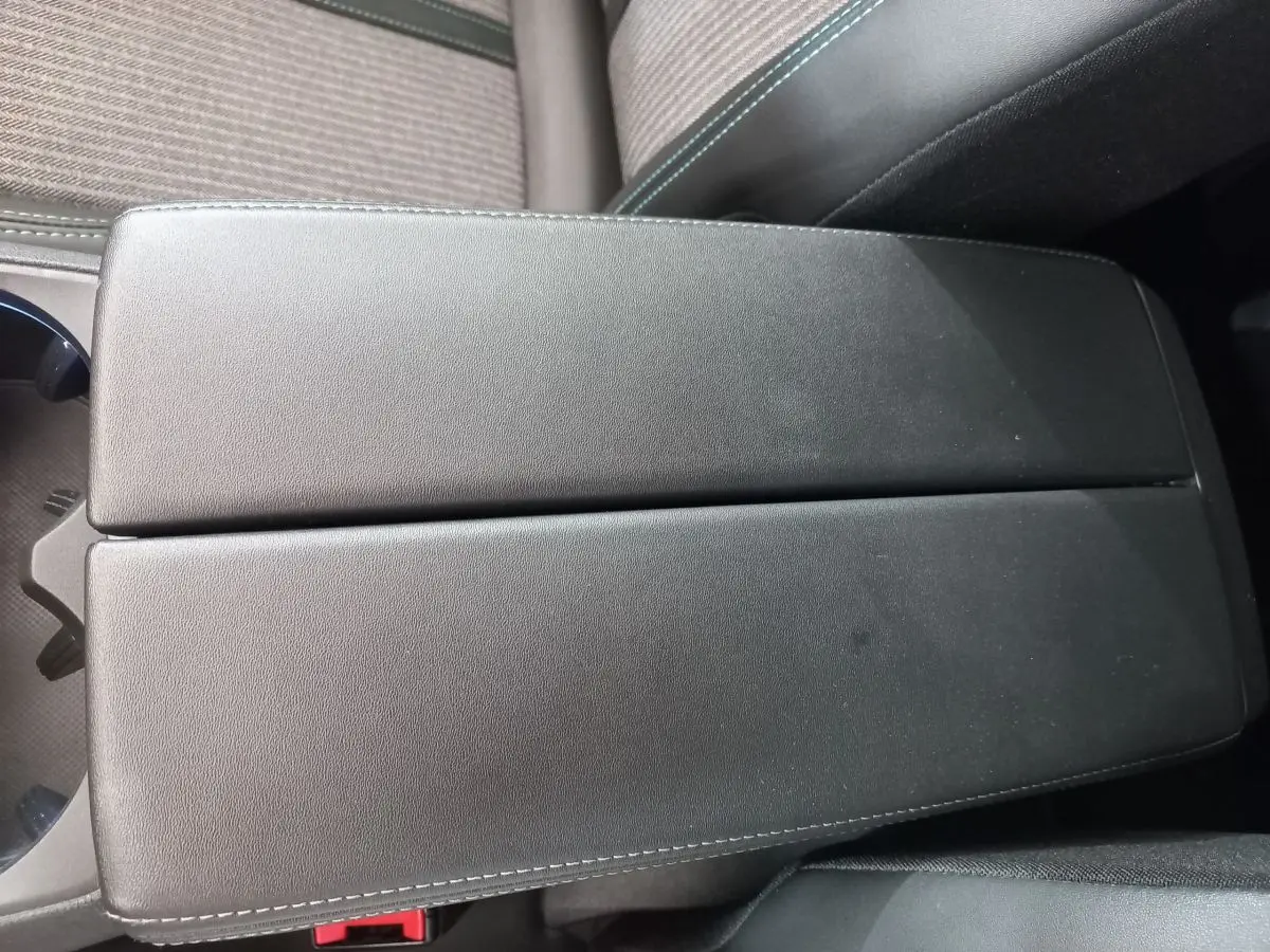 Vue rapprochée de l'accoudoir central noir en cuir avec surpiqûres blanches dans l'habitacle du Peugeot 5008 gris foncé.