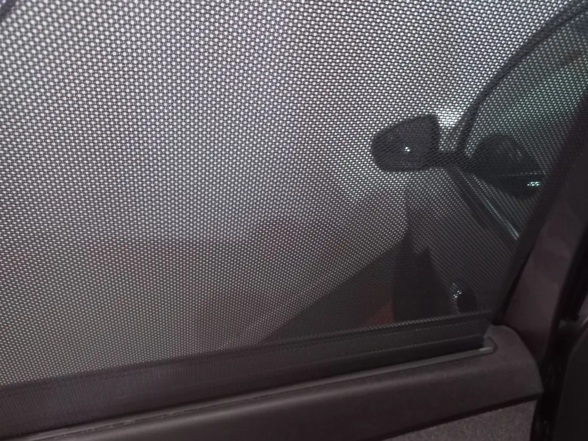 Vue partielle du côté droit du Peugeot 5008 gris foncé à travers un pare-soleil en maille sur la vitre arrière.