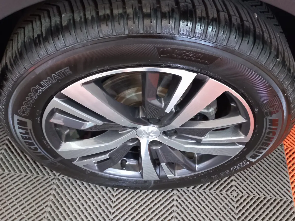 Gros plan sur la jante alliage gris foncé et pneu Michelin CrossClimate du Peugeot 5008, vue de dessus.