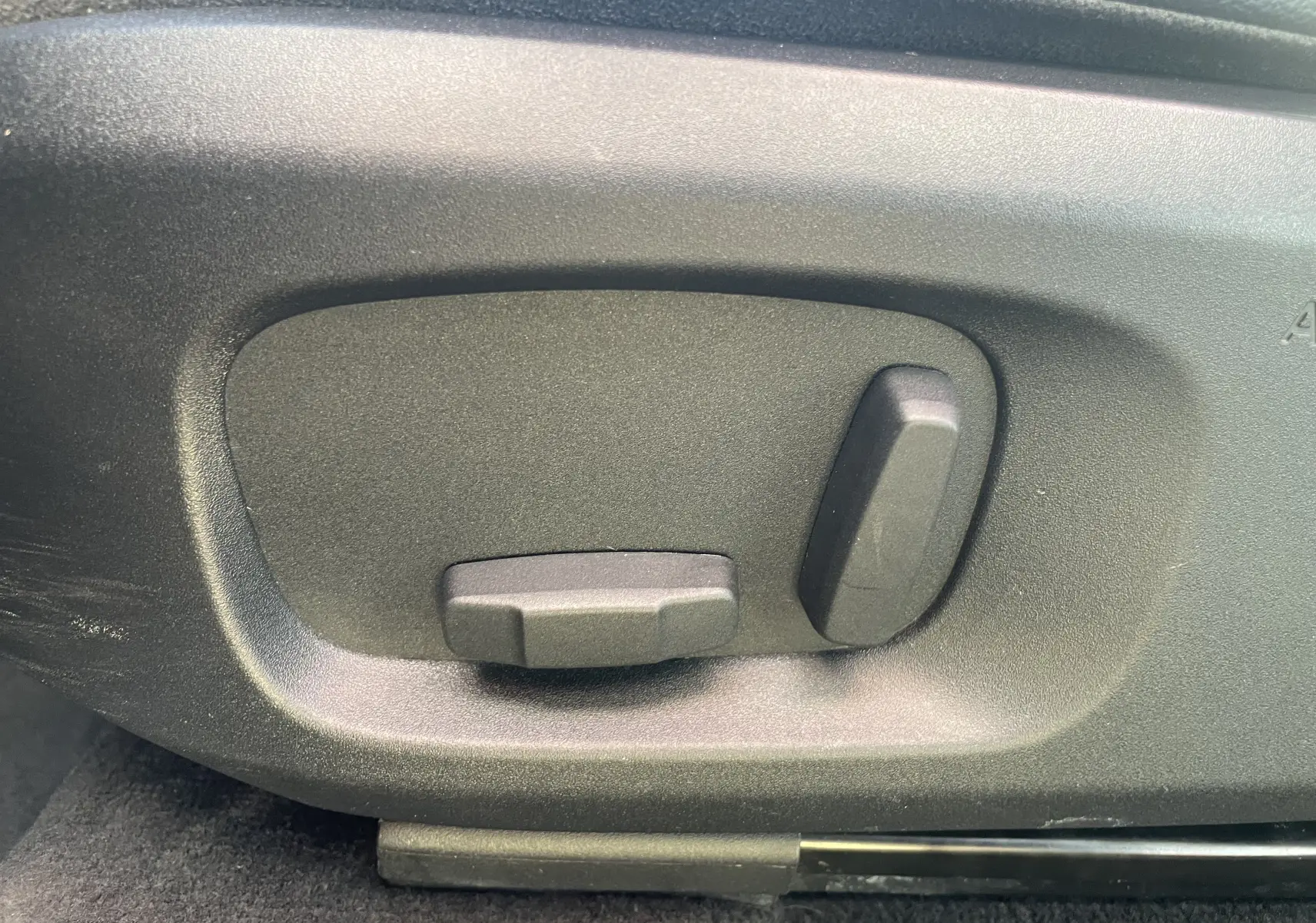 Détail des commandes de réglage électrique du siège avant dans un Range Rover Evoque noir, vue rapprochée intérieure.