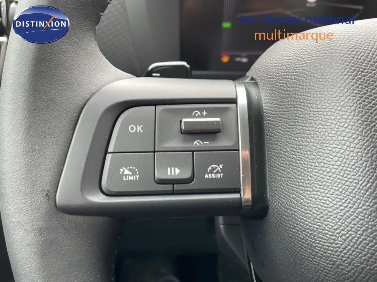 Gros plan sur les commandes au volant à gauche d'une Citroën C4 blanc métal, version PureTech 130ch avec régulateur et limiteur.