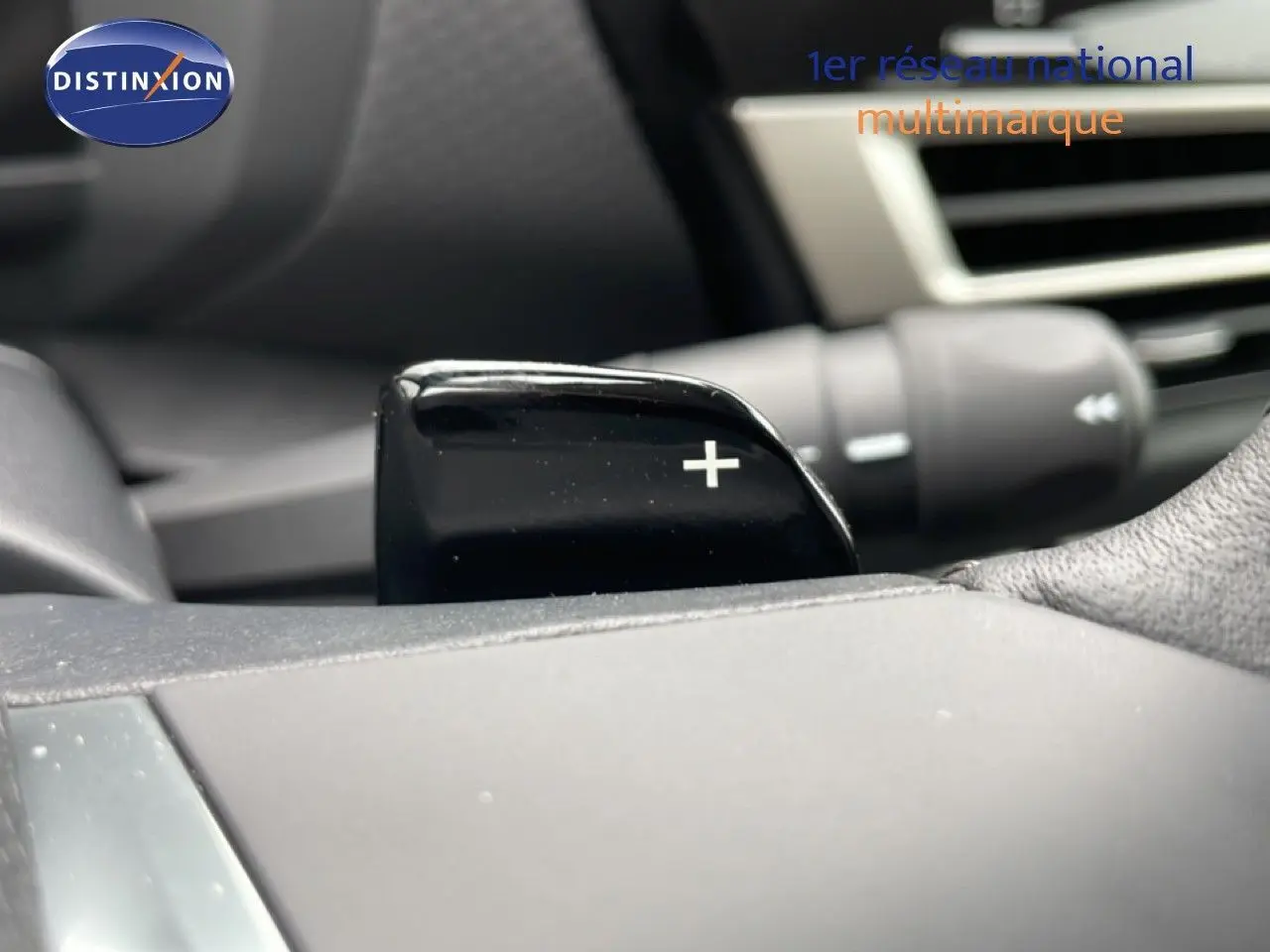 Gros plan sur la palette de changement de vitesse + côté droit du volant d’une Citroën C4 blanche métal.