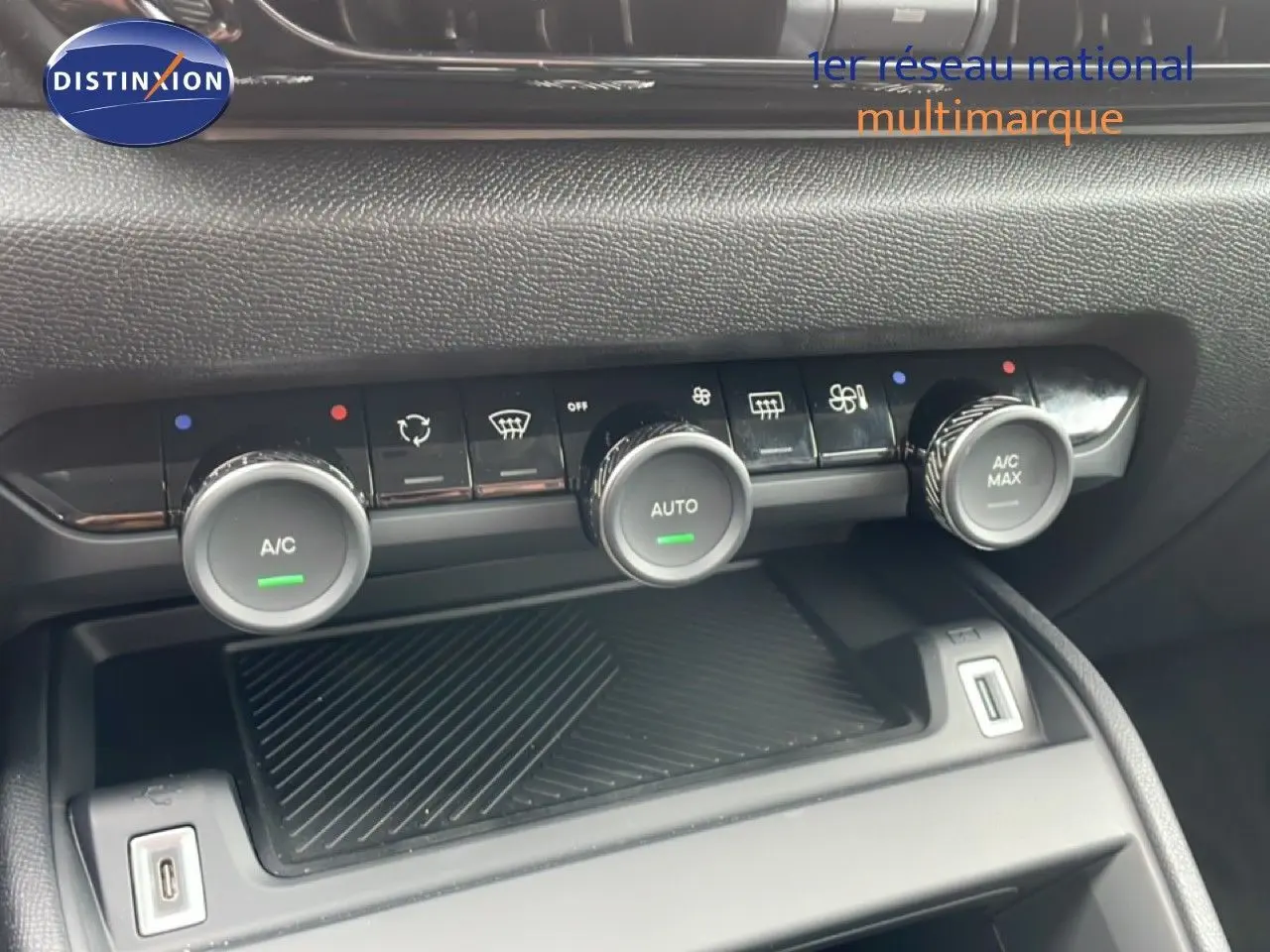 Gros plan sur la console centrale de la Citroën C4 blanche, montrant les commandes de climatisation et deux ports USB.