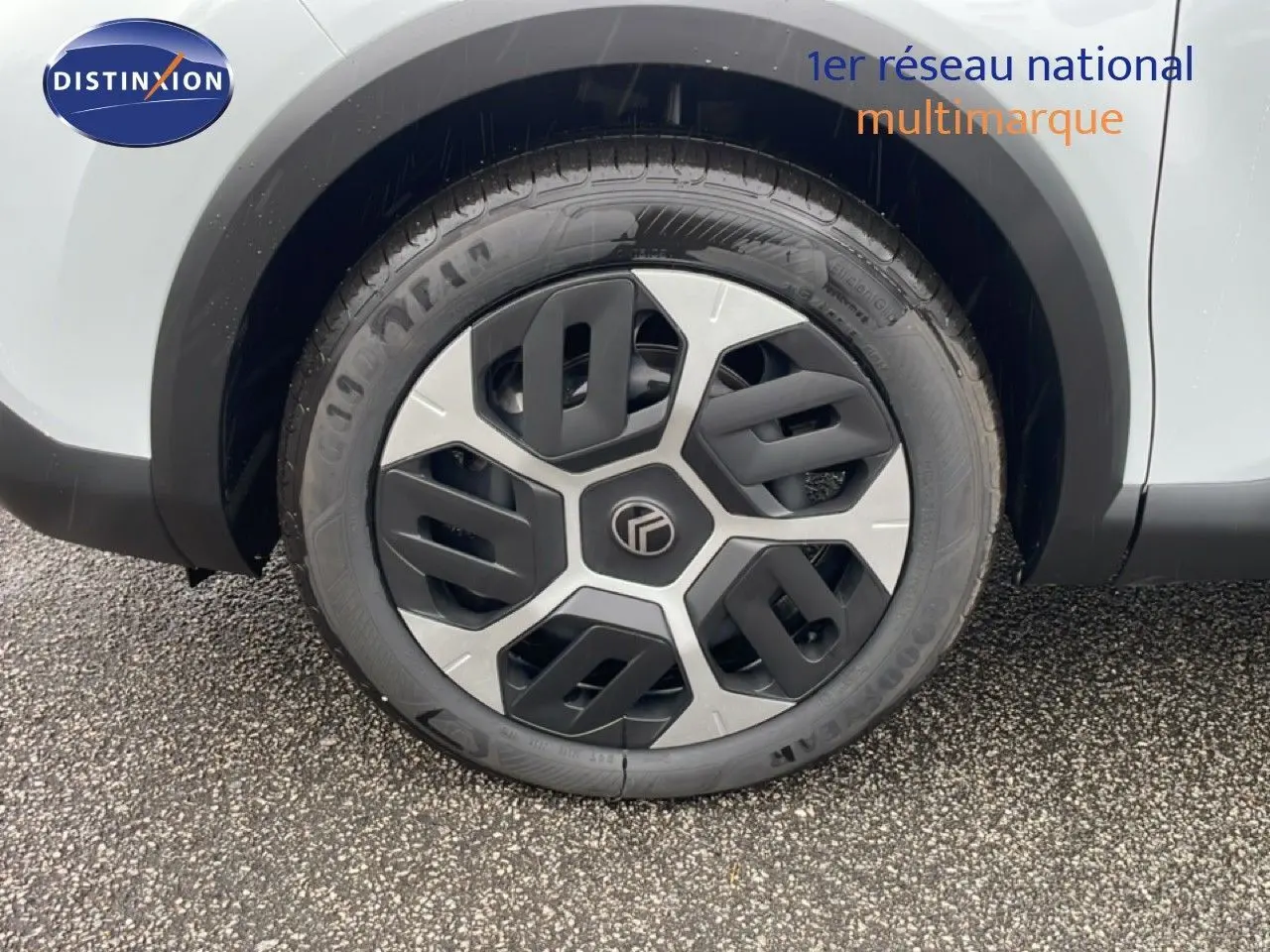 Gros plan sur la roue avant droite d'une Citroën C4 blanc métal, avec jante au design moderne bicolore.
