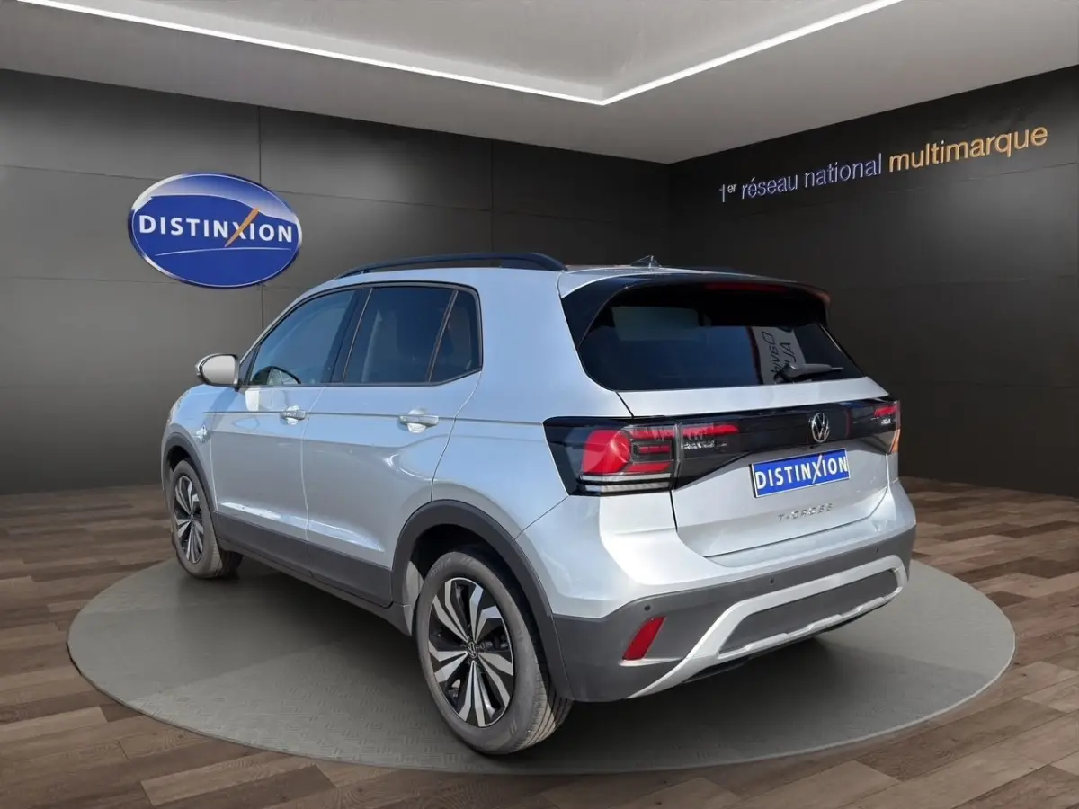 Vue 3/4 arrière droite d’un Volkswagen T-Cross gris clair avec feux arrière LED et jantes alliage bicolores.