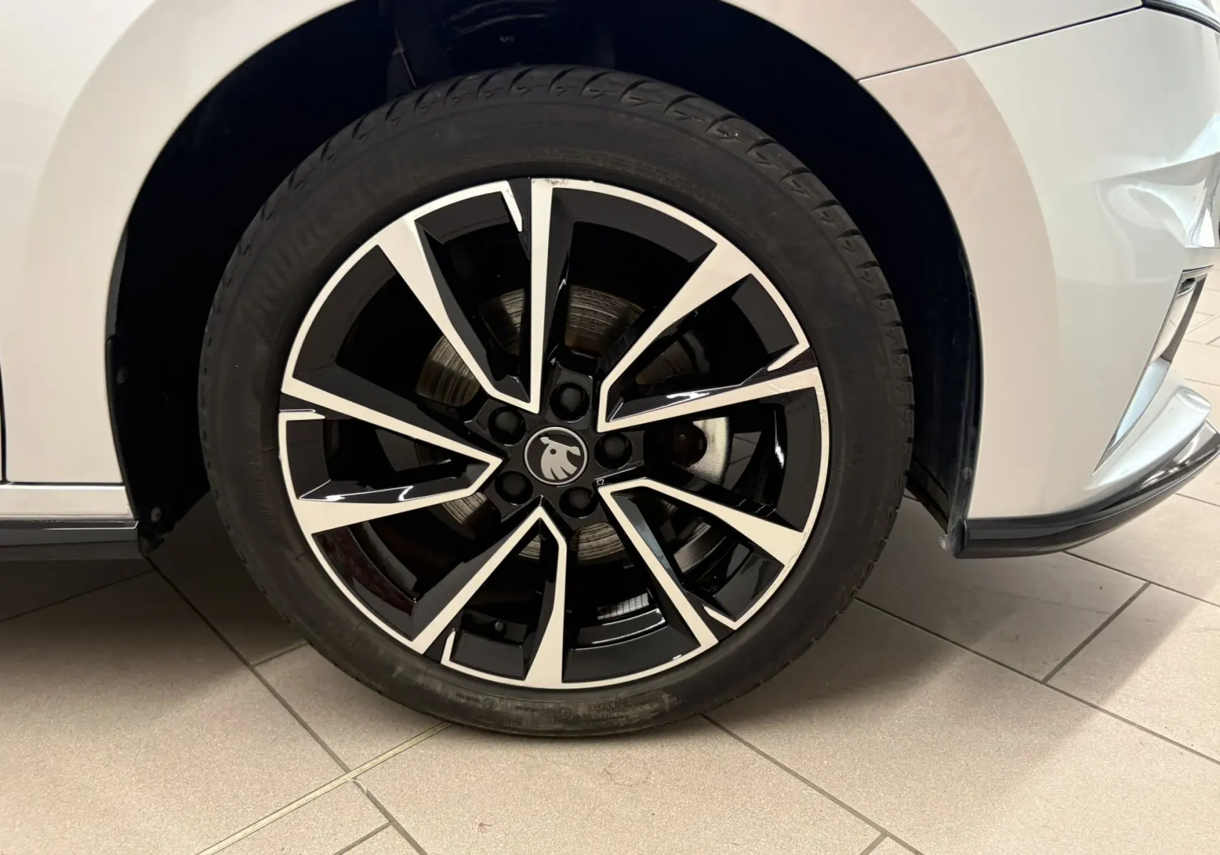Gros plan sur la roue avant droite d’une Skoda Fabia 2025 gris argent, jante alliage noire et argentée design Monte Carlo.