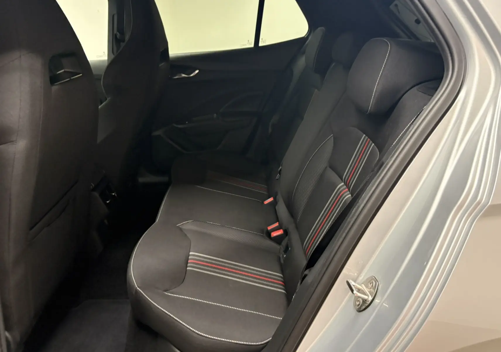 Vue intérieure côté droit des sièges arrière noirs avec surpiqûres blanches et bandes rouges d'une Skoda Fabia 2025 gris argent.