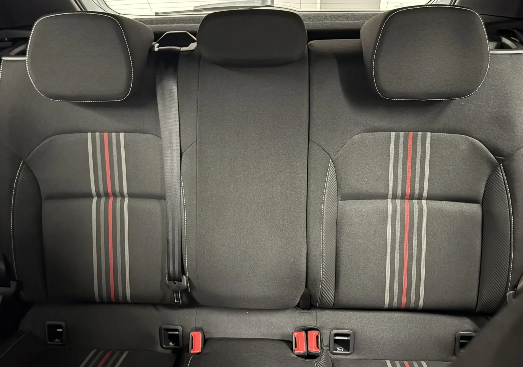 Vue arrière intérieure des sièges arrière de la Skoda Fabia Monte Carlo 2025, tissu noir avec bandes grises et rouges.