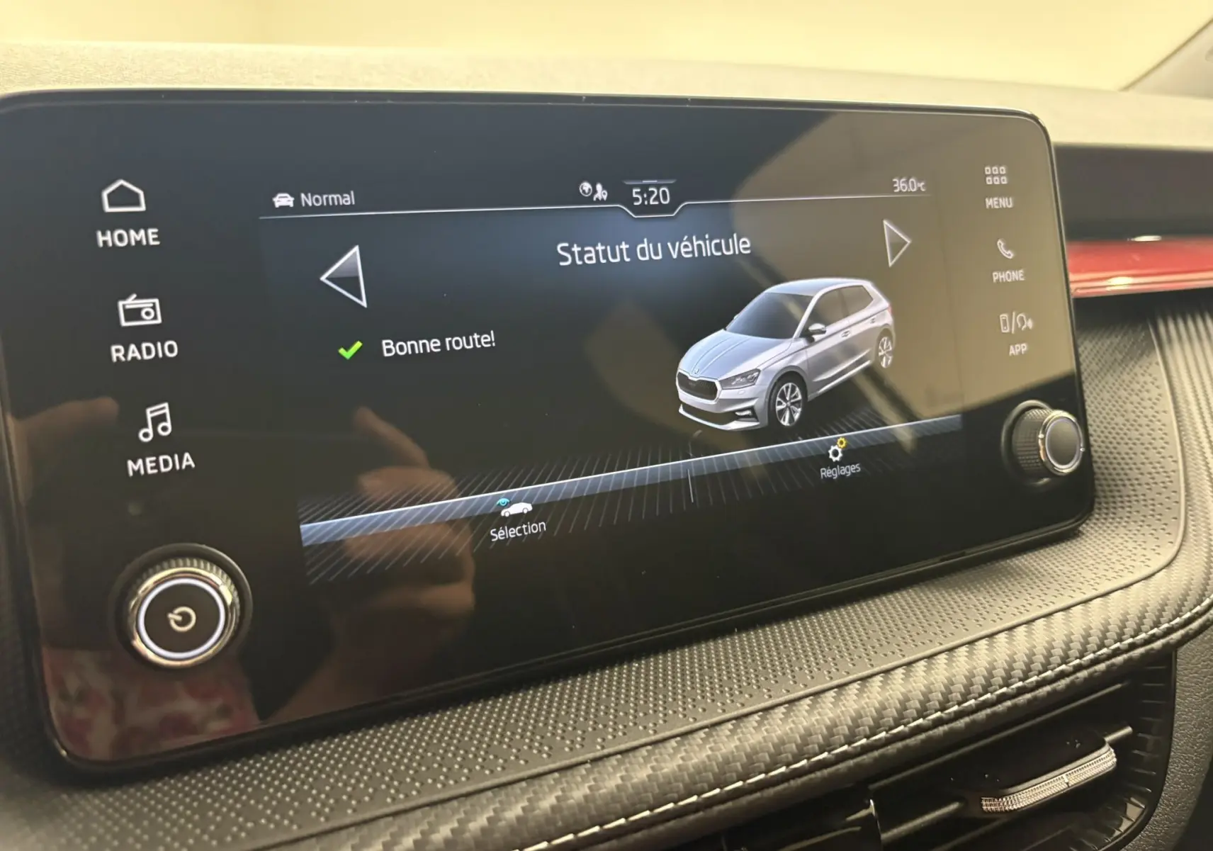 Écran tactile intérieur montrant le statut du véhicule Skoda Fabia gris argent en vue 3/4 avant, avec interface claire.