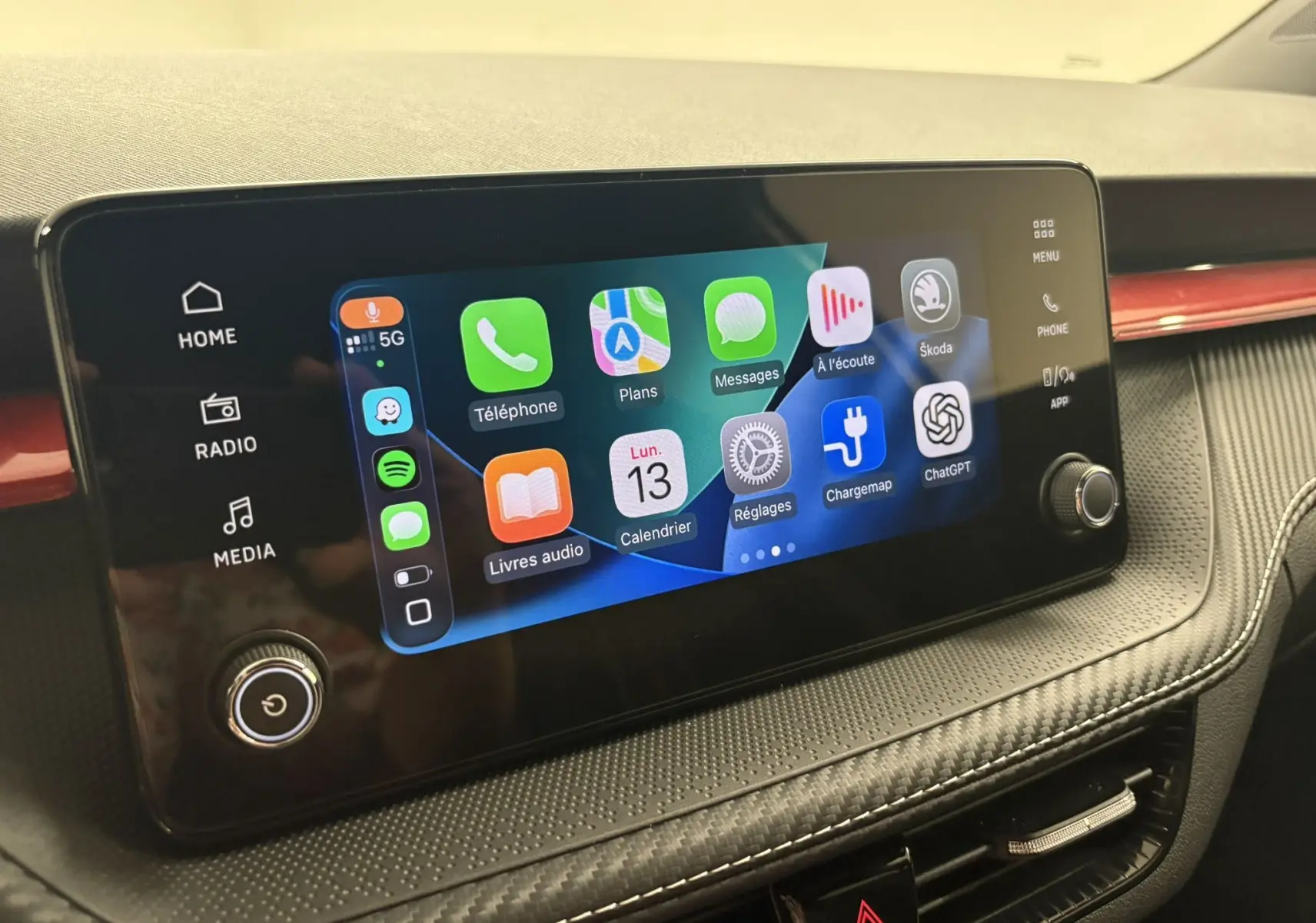 Écran tactile central de la Skoda Fabia 2025 avec interface connectée et tableau de bord gris avec insert rouge.