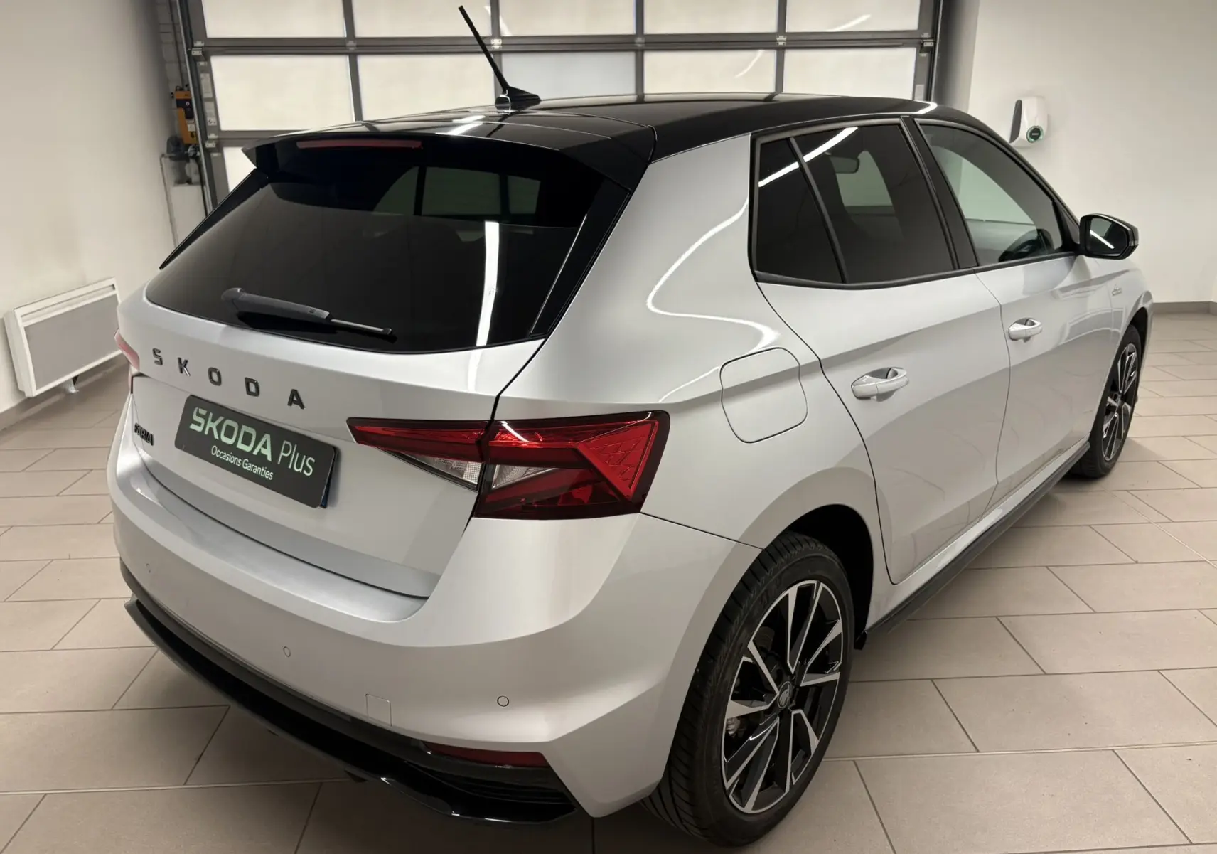 Vue 3/4 arrière droite d'une Skoda Fabia 2025 gris argent avec toit noir et jantes alliage noires.
