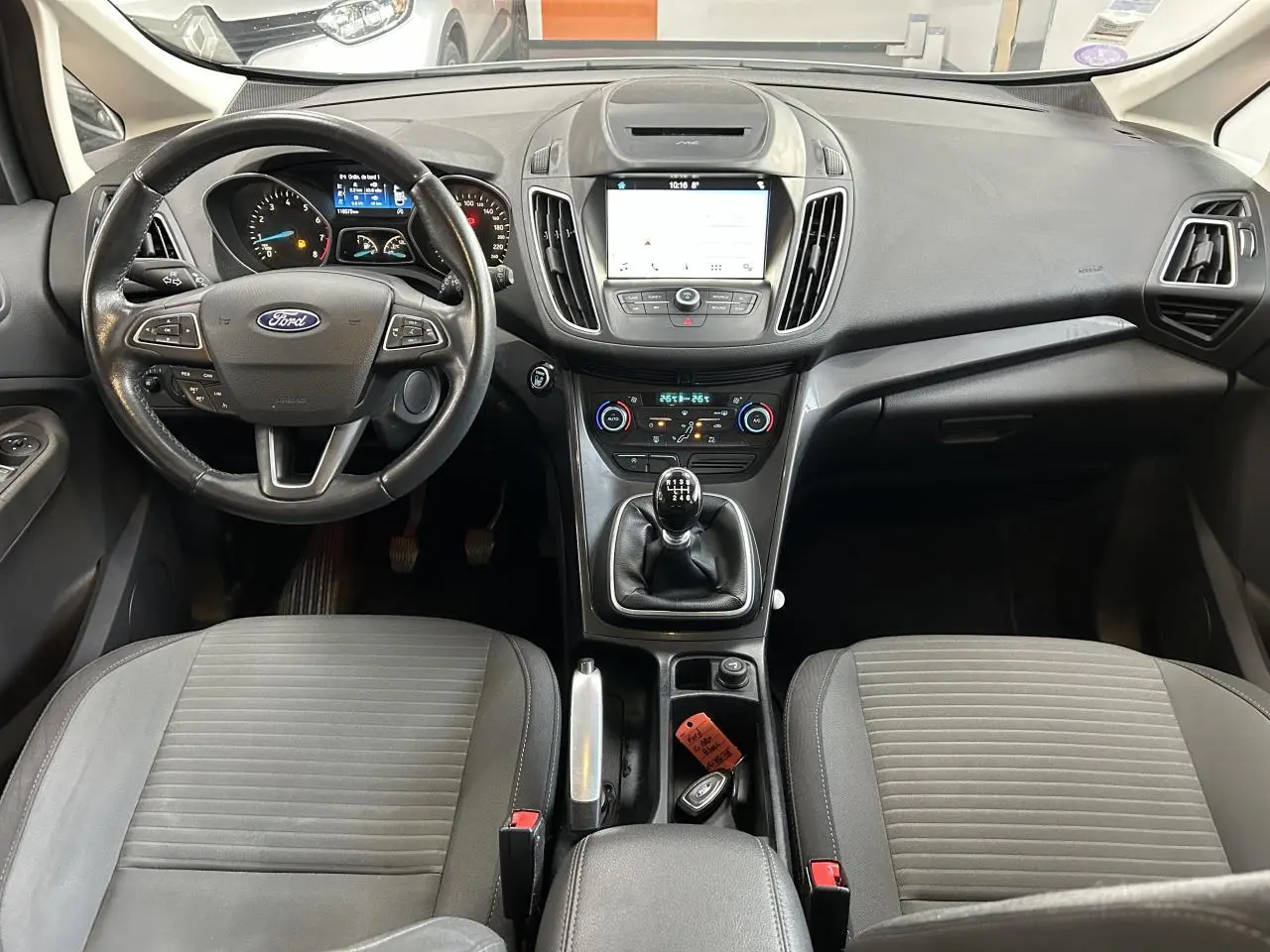 Vue intérieure du tableau de bord et console centrale d'une Ford C-MAX 2018 avec volant multifonction et boîte manuelle.