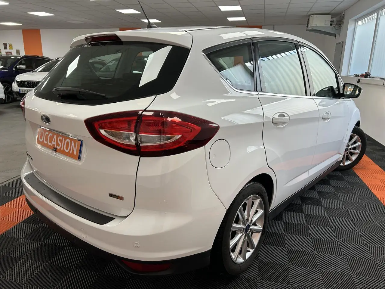 Vue 3/4 arrière droite d'une Ford C-MAX blanche 2018 avec jantes alliage 16 pouces et feux arrière distinctifs.