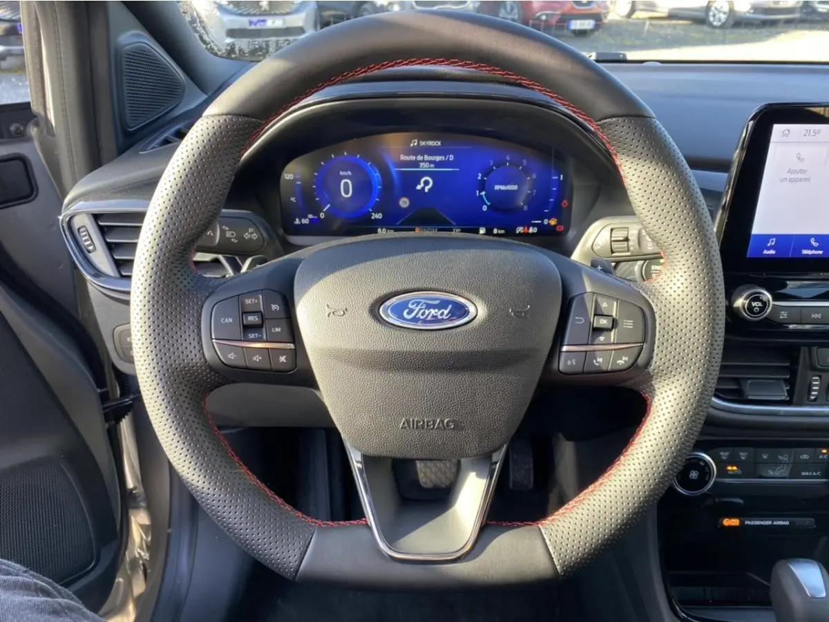 Vue centrée du volant perforé avec surpiqûres rouges et tableau de bord numérique du Ford Puma gris 2021 ST Line.