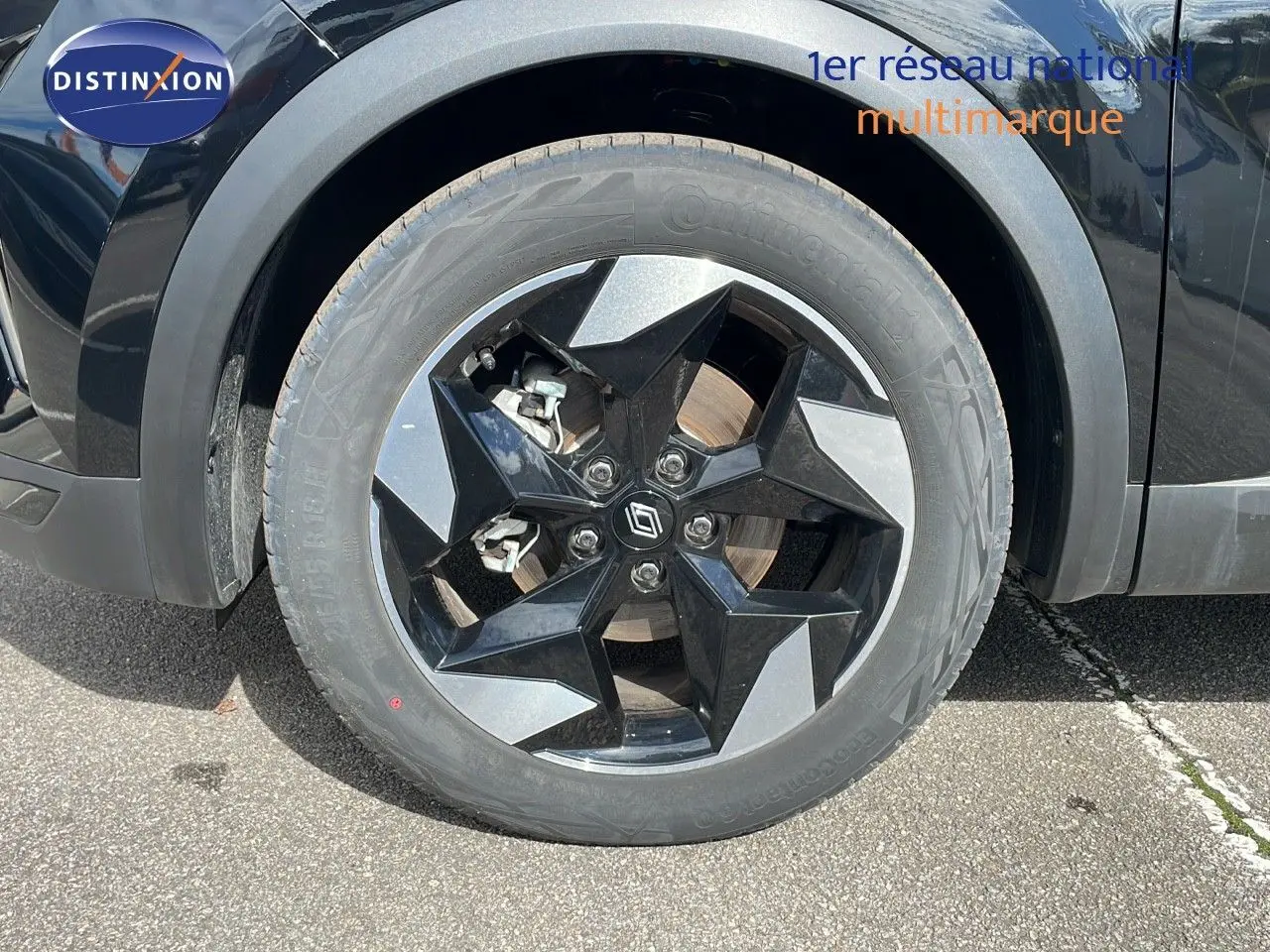 Gros plan sur la roue avant gauche du Renault Captur noir étoile métal avec jante noire et gris métallisé.