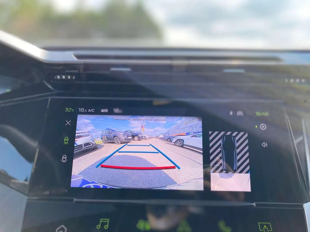 Écran central de la Peugeot 308 GT 2025 montrant la caméra de recul avec vue arrière sur un parking en gris selenium.