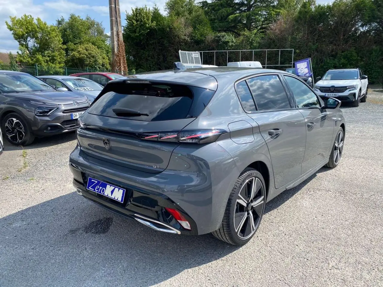 Peugeot 308 GT gris selenium vue 3/4 arrière droit, avec feux arrière fins et jantes alliage distinctives.