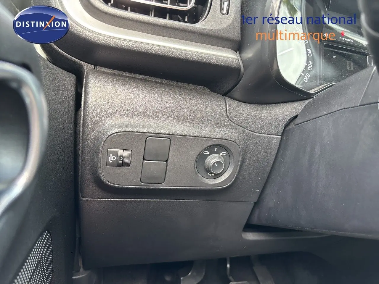 Détail du tableau de bord côté gauche de la Citroën C3 blanche, montrant les commandes de réglage des phares et des rétroviseurs.