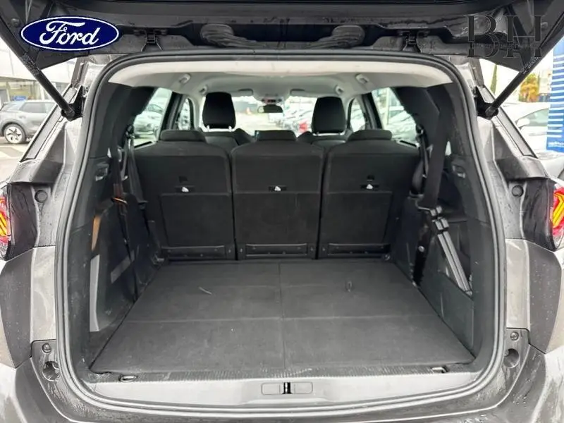 Coffre ouvert vu de l'arrière d'un Peugeot 5008 gris Platinium avec banquette arrière en tissu noir relevée.