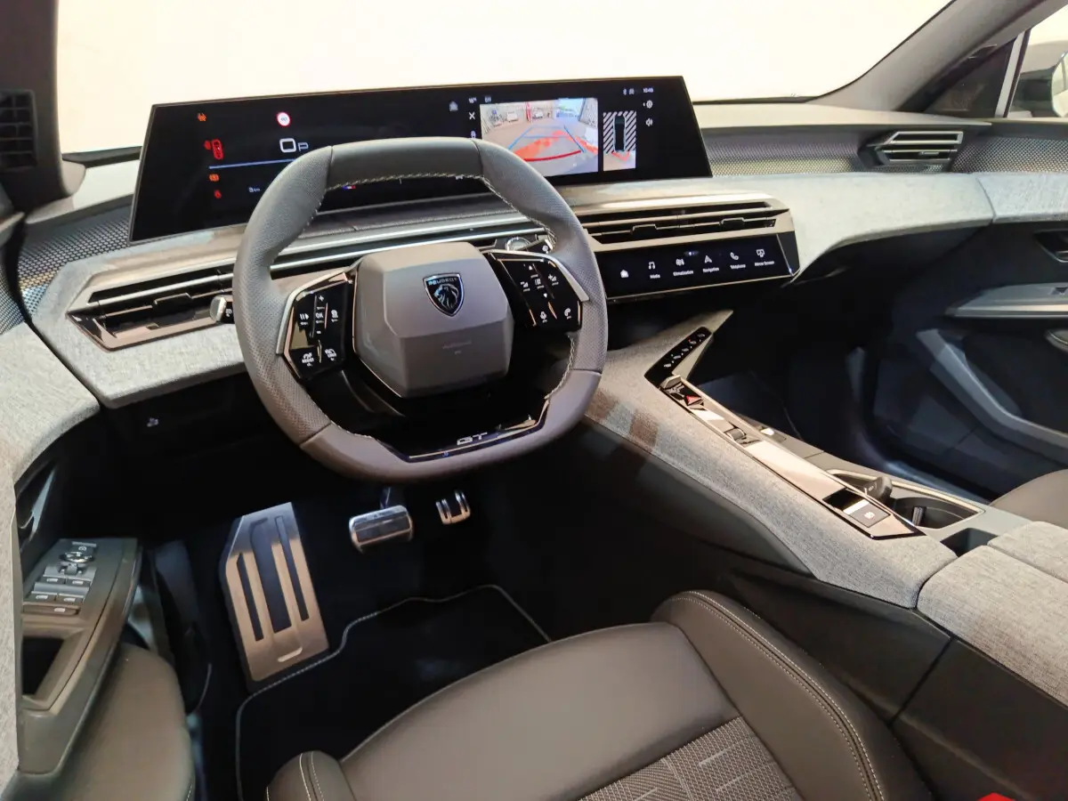 Vue intérieure avant du Peugeot 3008 1.2 Hybrid 145 GT, volant compact, écran tactile large et finition tissu gris.