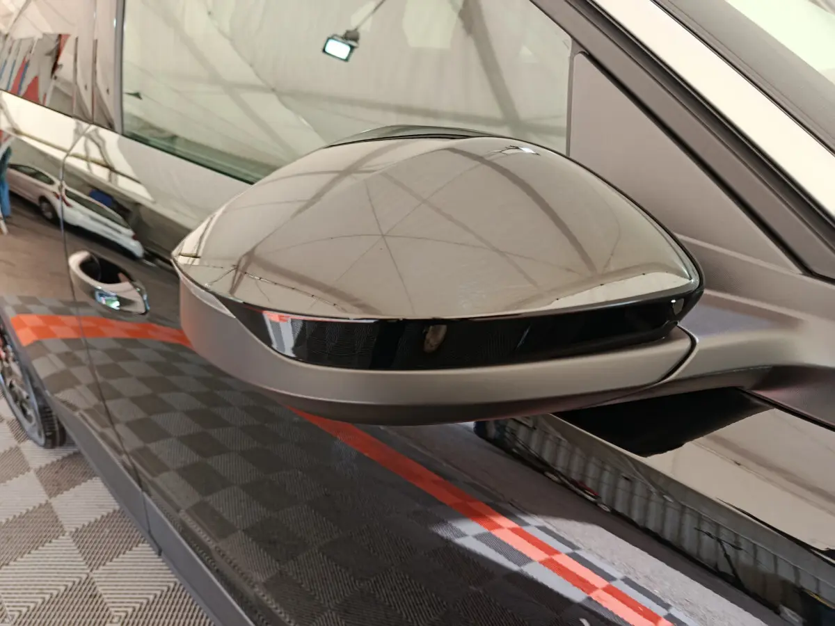 Rétroviseur côté gauche noir brillant du Peugeot 3008 2025, reflet du capot et de l'environnement intérieur.