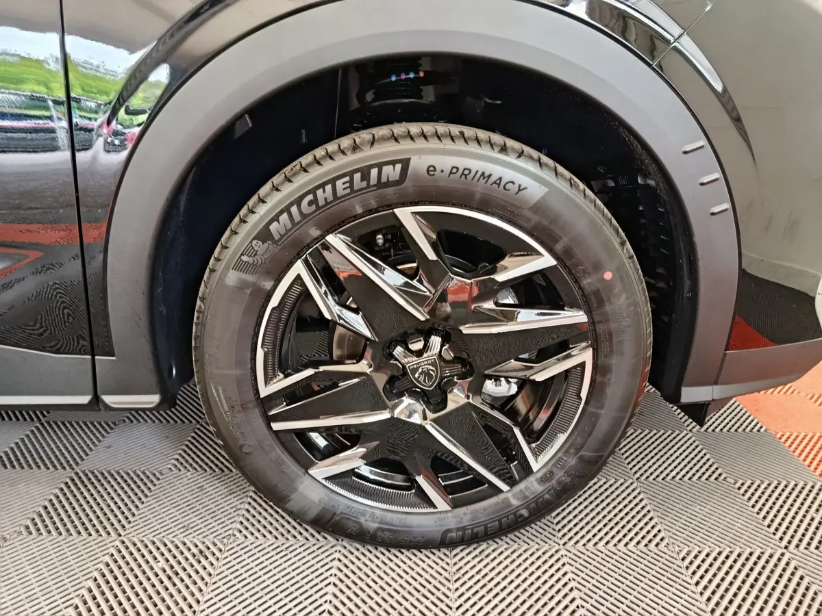 Gros plan sur la roue avant droite noire du Peugeot 3008 1.2 Hybrid 145 GT avec jante alliage brillante et pneu Michelin.