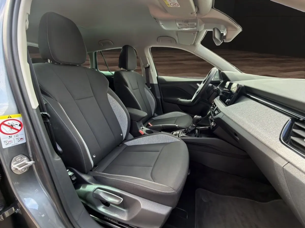 Vue intérieure côté conducteur de la Skoda Scala 2025 gris foncé, montrant sièges tissu bicolore et tableau de bord moderne.