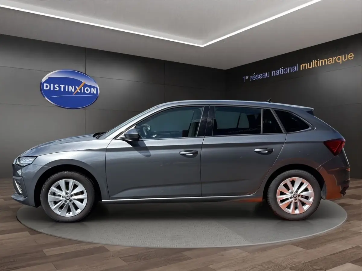 Profil côté gauche d'une Skoda Scala gris foncé exposée en intérieur avec jantes alliage et vitres teintées.