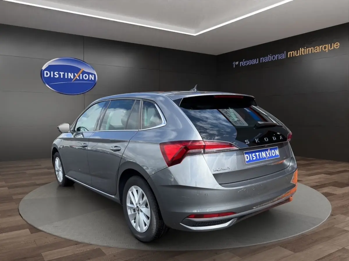 Vue 3/4 arrière droite d'une Skoda Scala gris foncé avec feux arrière LED et logo distinctif au showroom.