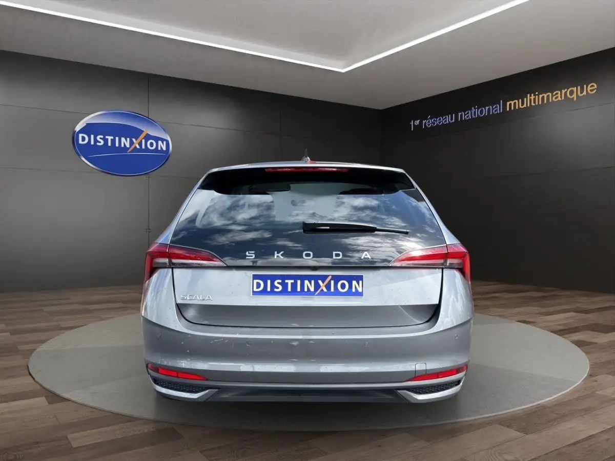 Vue arrière d'une Skoda Scala gris foncé, avec feux LED et logo distinctif sur fond de showroom.