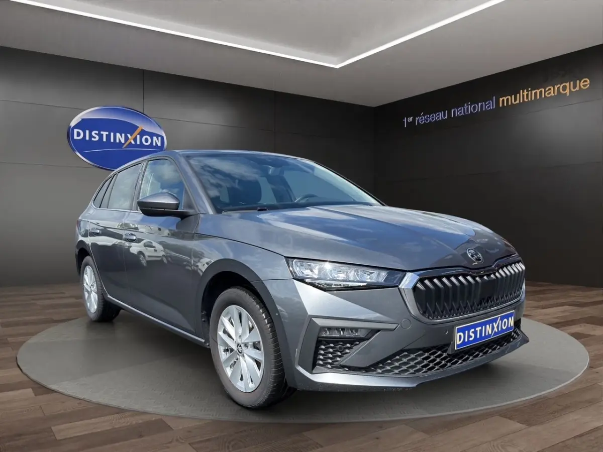 Vue 3/4 avant d'une Skoda Scala gris foncé avec calandre chromée et phares LED, sur fond de showroom Distinxion.