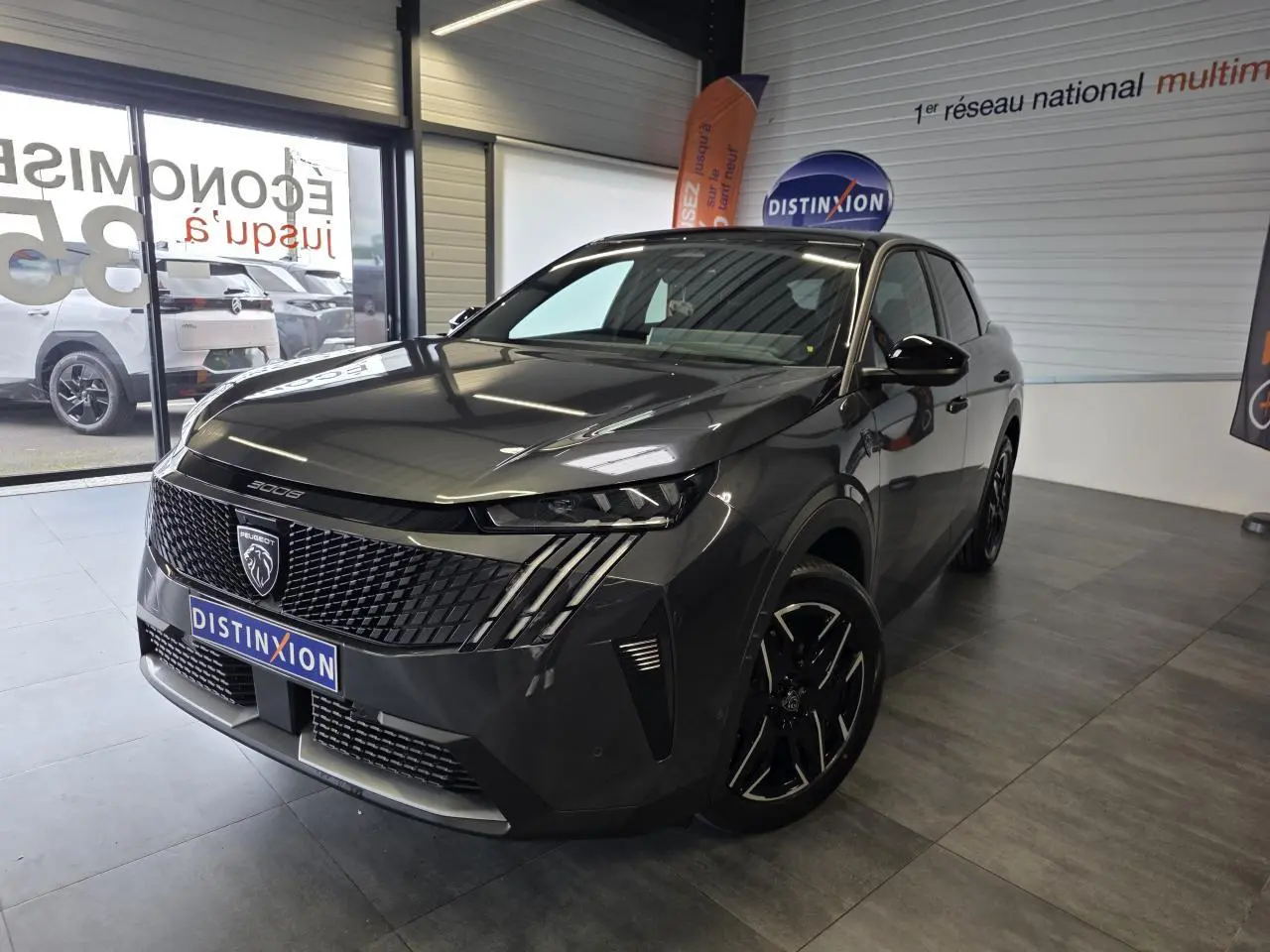Peugeot 3008 gris titanium en 3/4 avant droit, avec calandre noire distinctive et jantes noires en concession.