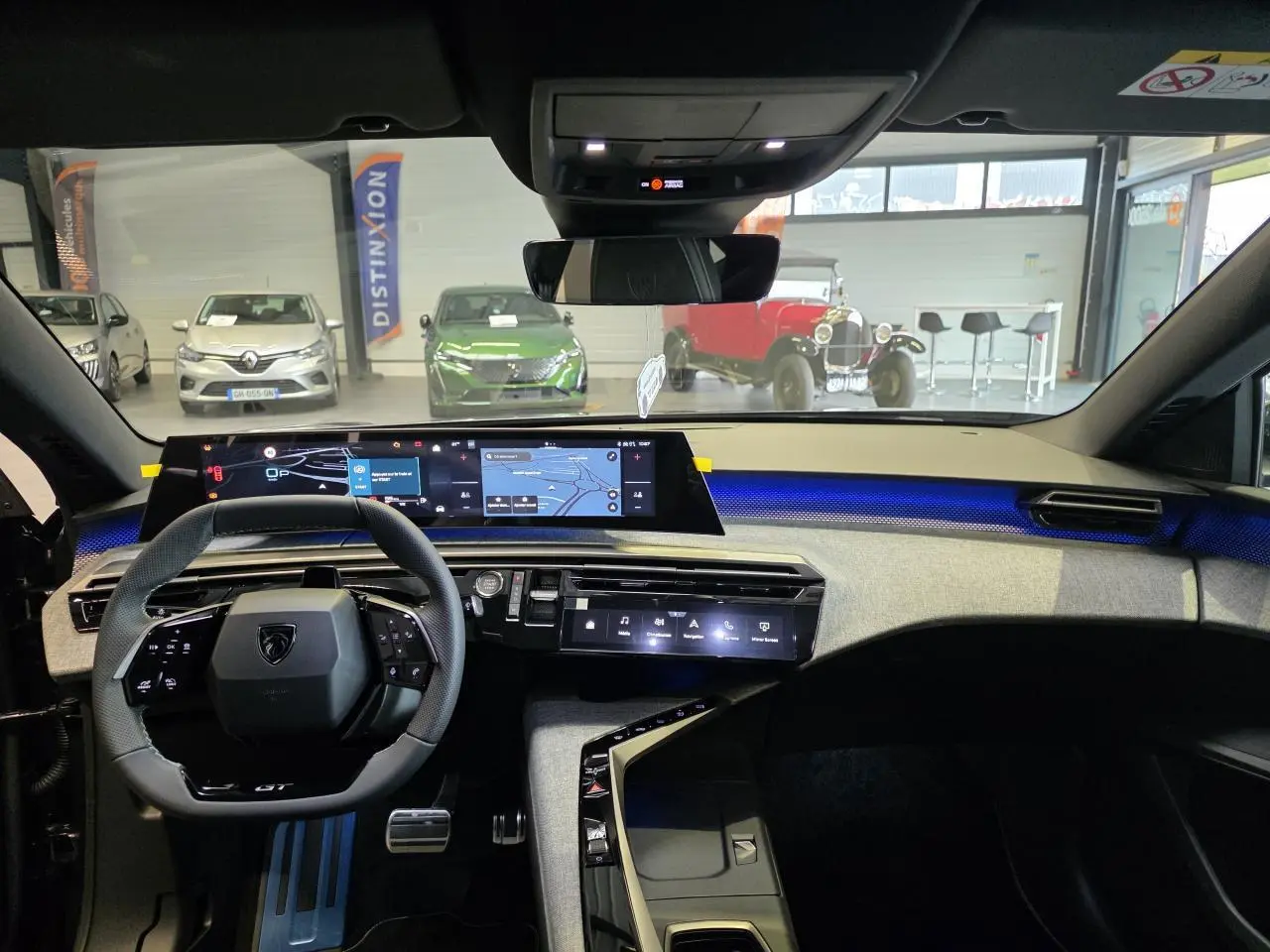 Vue intérieure du tableau de bord du Peugeot 3008 gris titanium 2026, avec écran numérique panoramique et éclairage d'ambiance bleu.