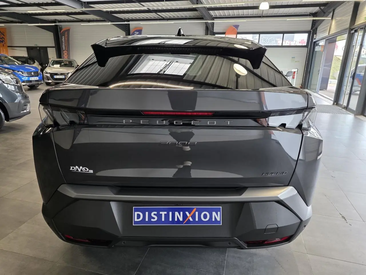 Vue arrière d'un Peugeot 3008 gris titanium hybride 2026 en showroom, avec logo et feux distinctifs visibles.