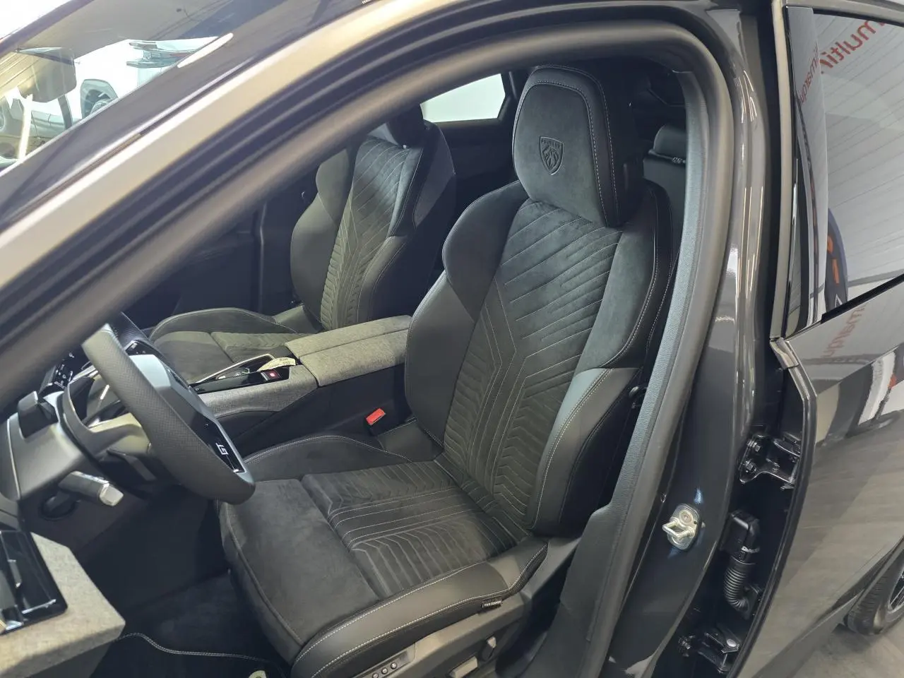 Vue intérieure côté conducteur du Peugeot 3008 2026 gris titanium, mettant en valeur les sièges sport en cuir et alcantara avec logo GT brodé.