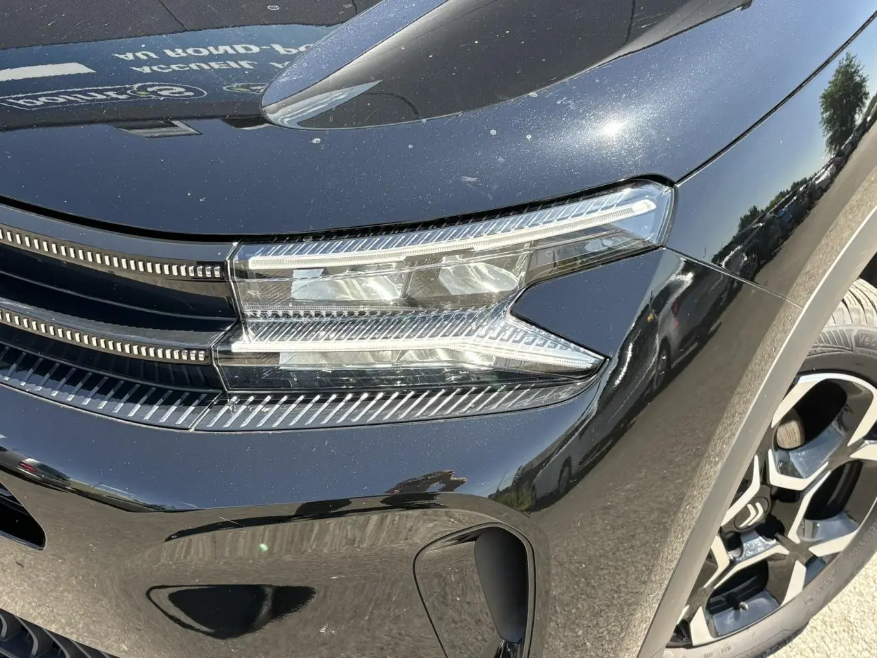 Gros plan sur le phare avant droit et la calandre noire Perla du Citroën C5 Aircross Hybrid 2025.