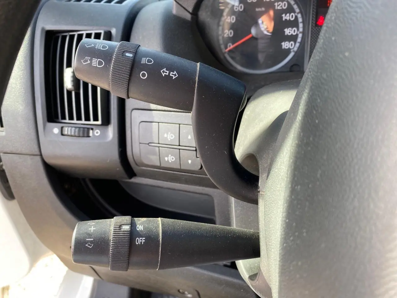Gros plan sur les commandes de clignotants et essuie-glace du tableau de bord d'un Citroën Jumper blanc de 2013.