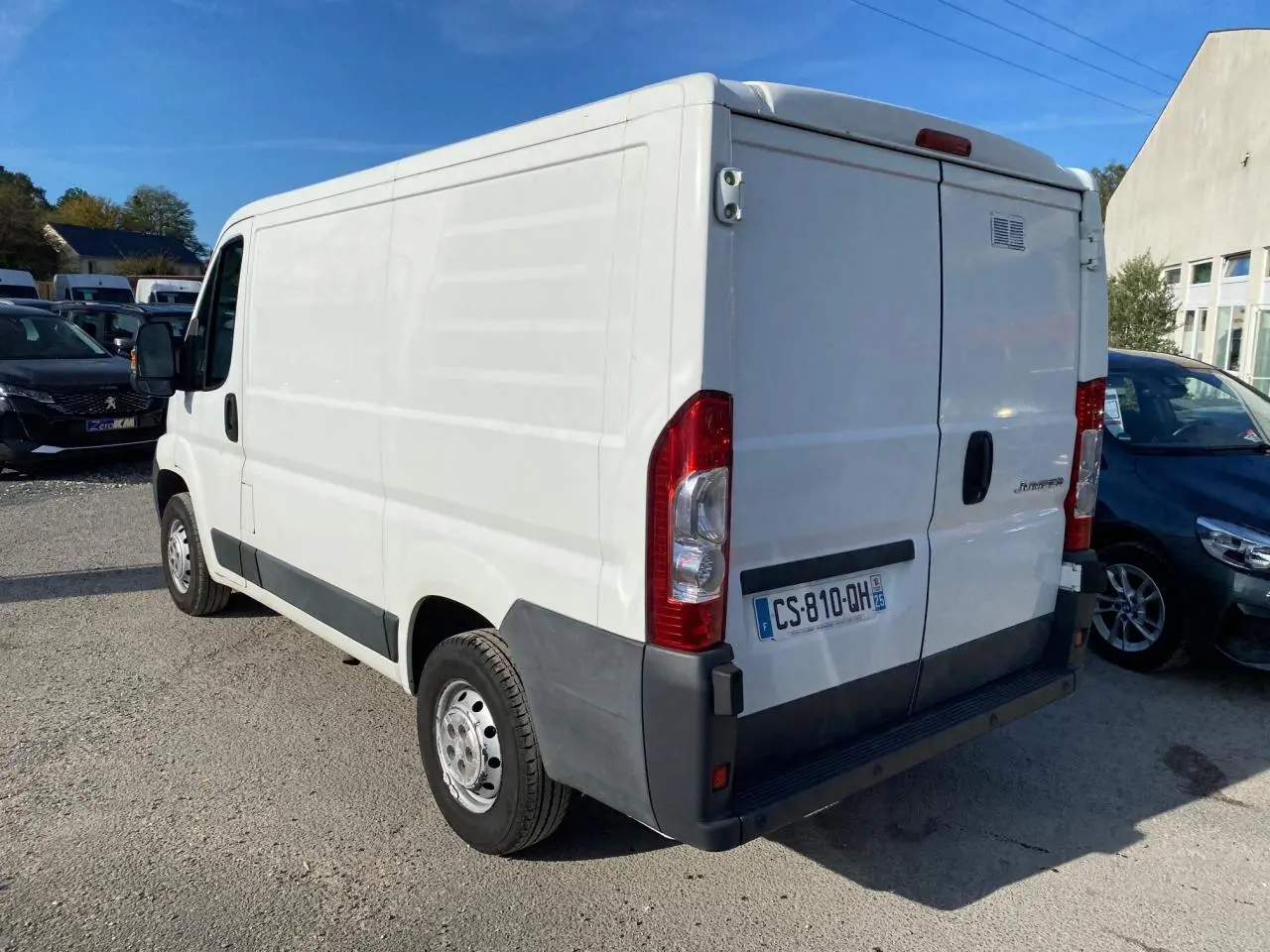 Vue 3/4 arrière droite d'un utilitaire blanc Citroën Jumper 2013 avec attelage et plaques françaises.