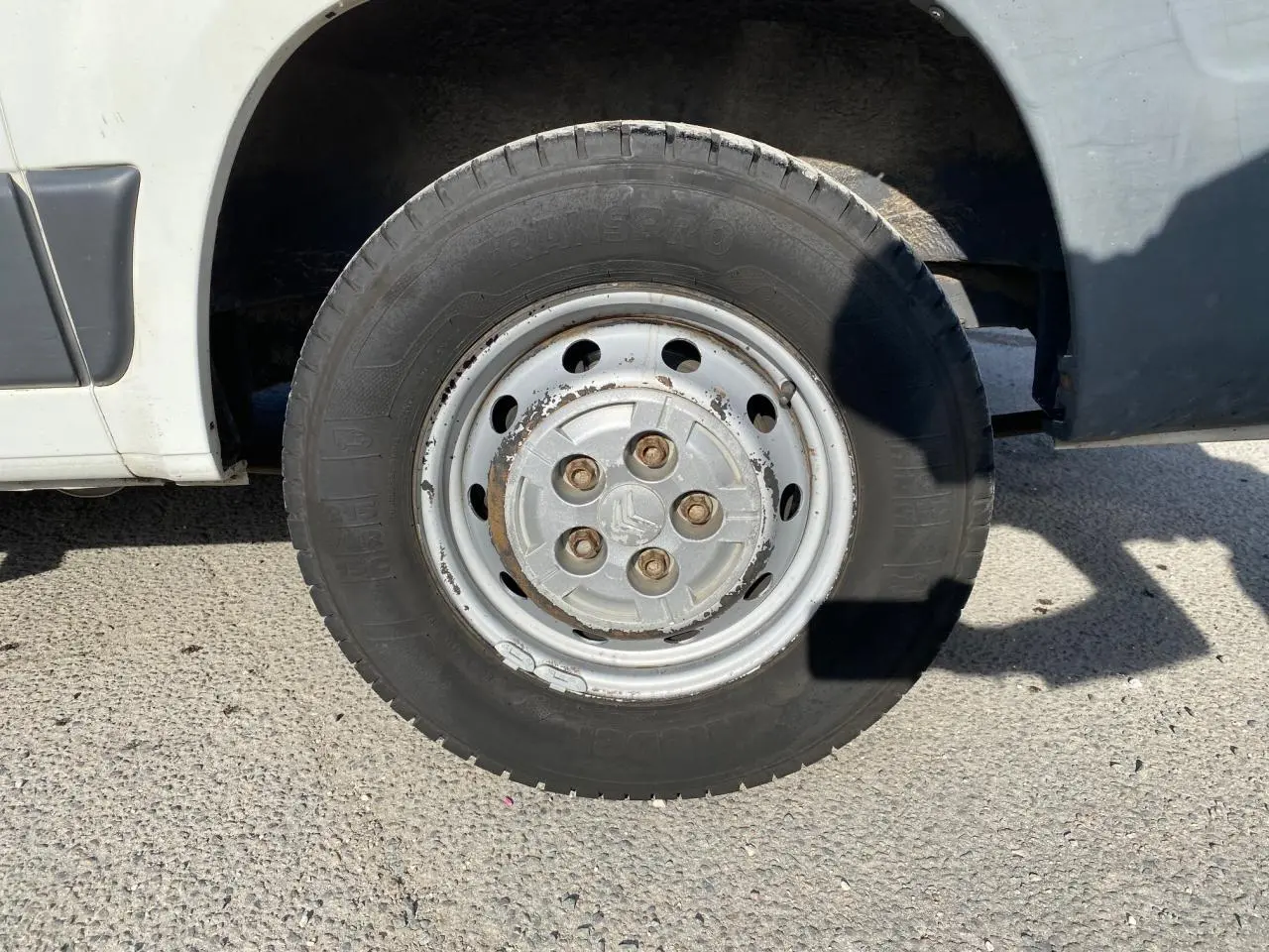 Gros plan sur la roue avant droite d'un Citroën Jumper blanc de 2013 avec jante acier et écrous rouillés.