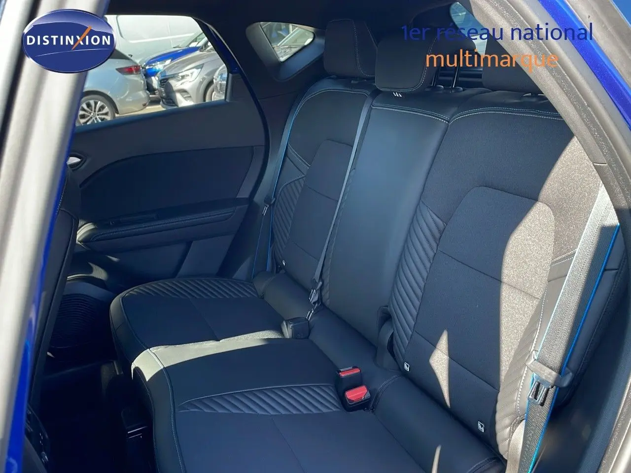 Vue intérieure sur la banquette arrière noire avec surpiqûres bleues du Renault Captur E-Tech hybride 2025, porte ouverte côté droit.