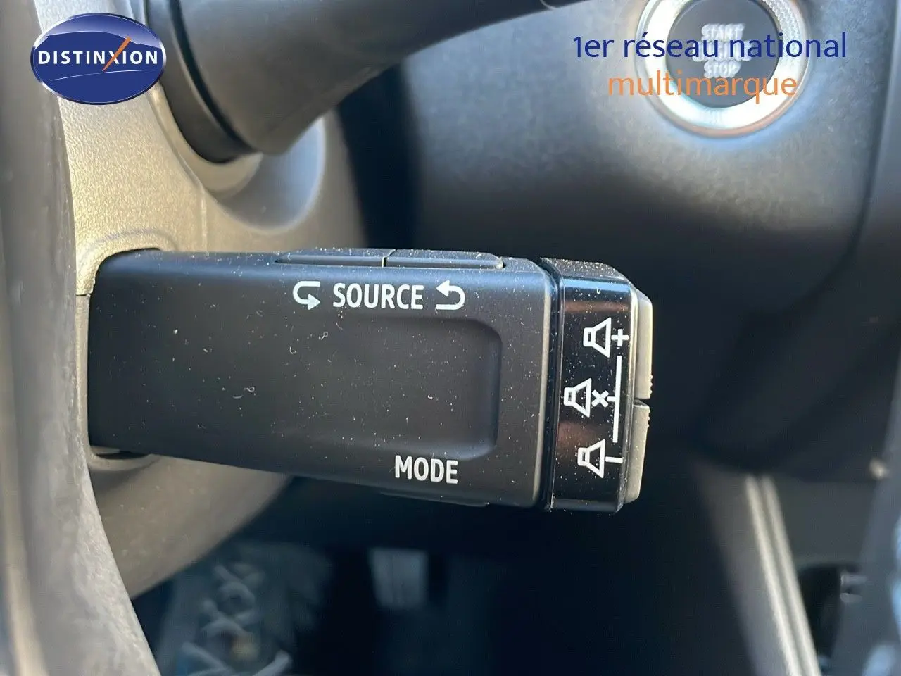 Gros plan sur la commande au volant gauche du Renault Captur E-Tech hybride bleu, avec bouton source et mode visibles.